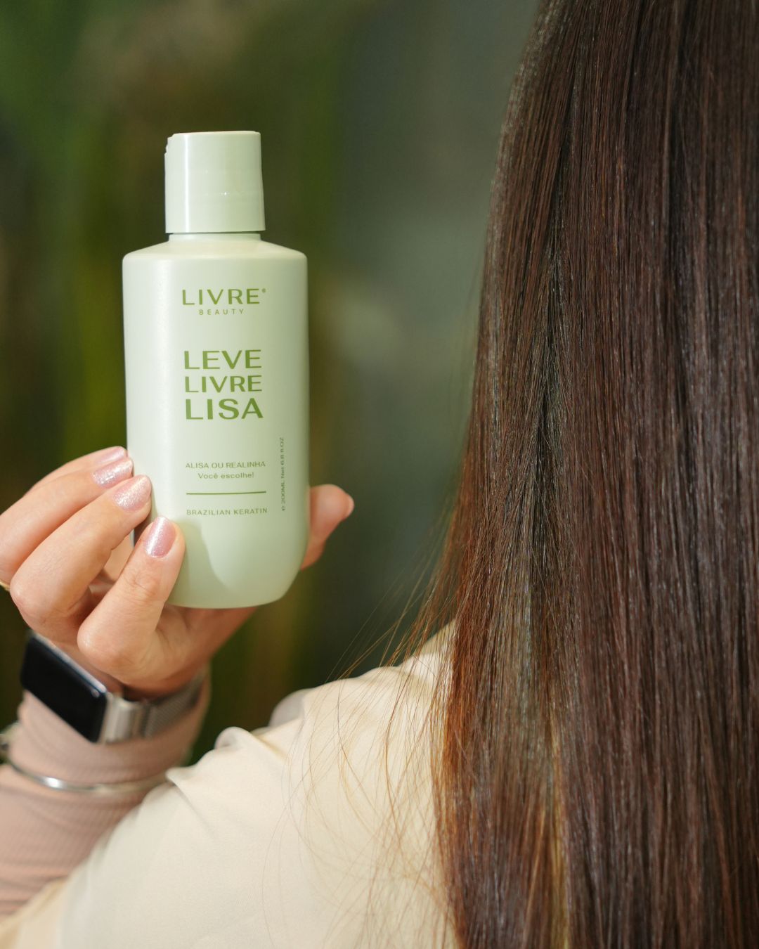 Mão segurando o frasco da Progressiva Leve, Livre e Lisa ao lado de cabelo liso
