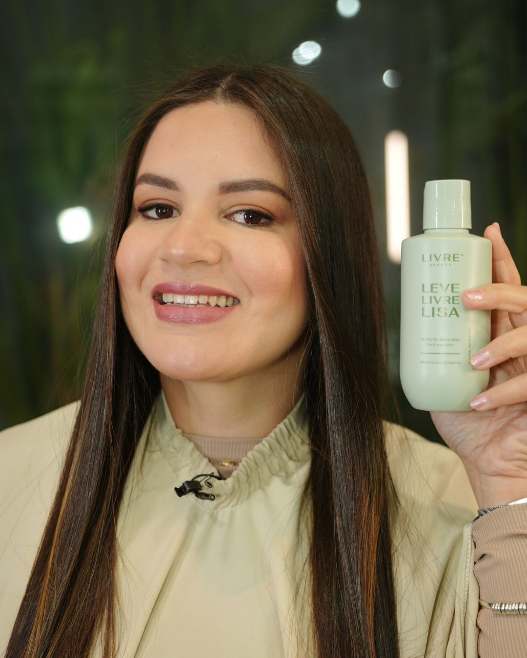 Modelo sorrindo, de cabelo liso, segurando o frasco da Progressiva Leve, Livre e Lisa