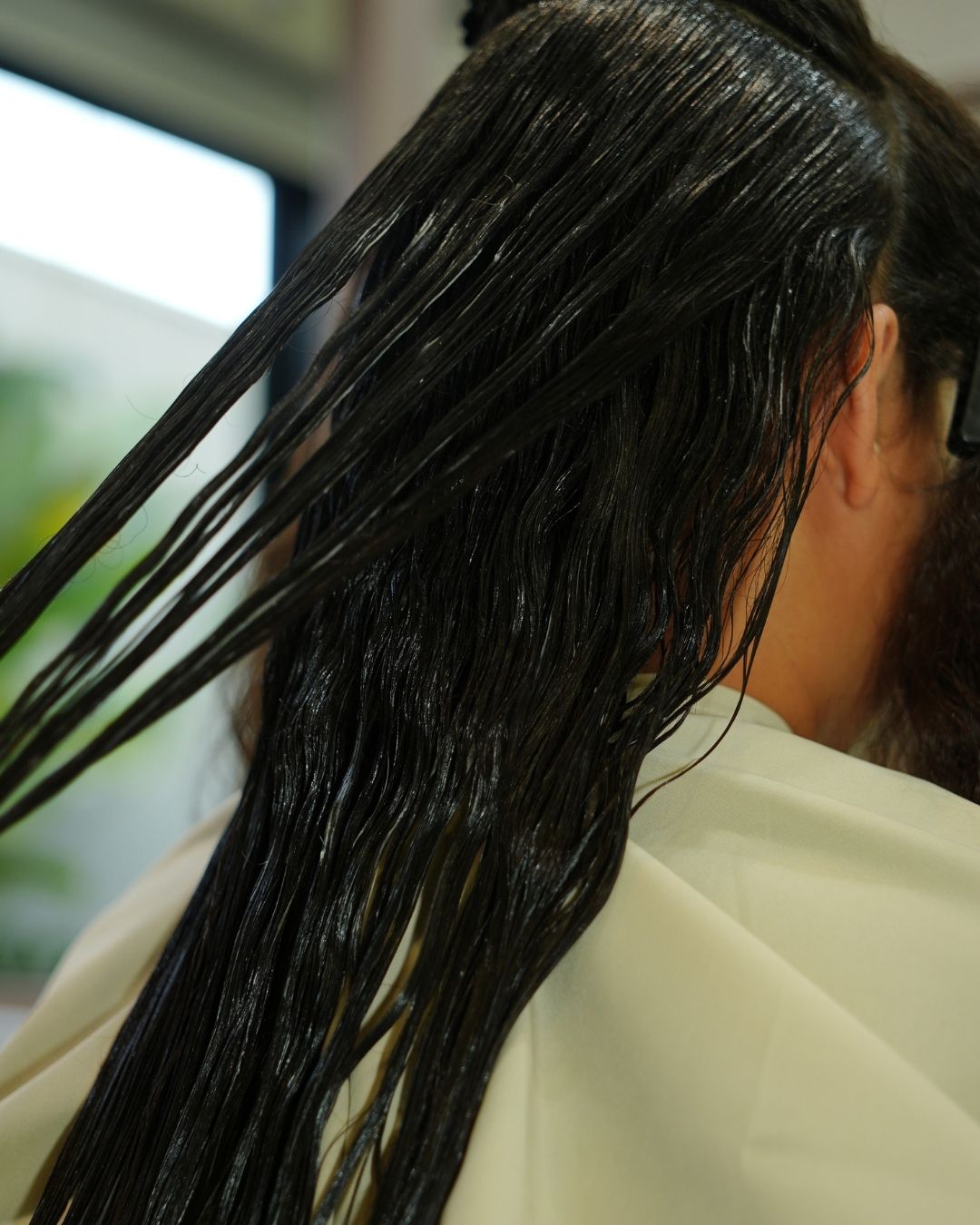 Cabelo molhado sendo separado em mechas durante a aplicação